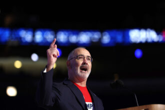 United Auto Workers President Shawn Fain at the Democratic National Convention on Aug. 19. He spoke about Lordstown, Ohio, where an auto assembly plant closed during the Trump administration and a battery manufacturing plant opened during the Biden administration. (Photo by Justin Sullivan/Getty Images)