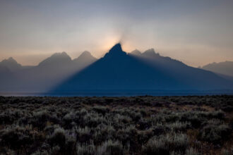 The sun sets behind the mountains at Grand Teton National Park in Wyoming, shrouded in smoke from regional wildfires on July 14, 2021. Credit: Natalie Behring/Getty Images