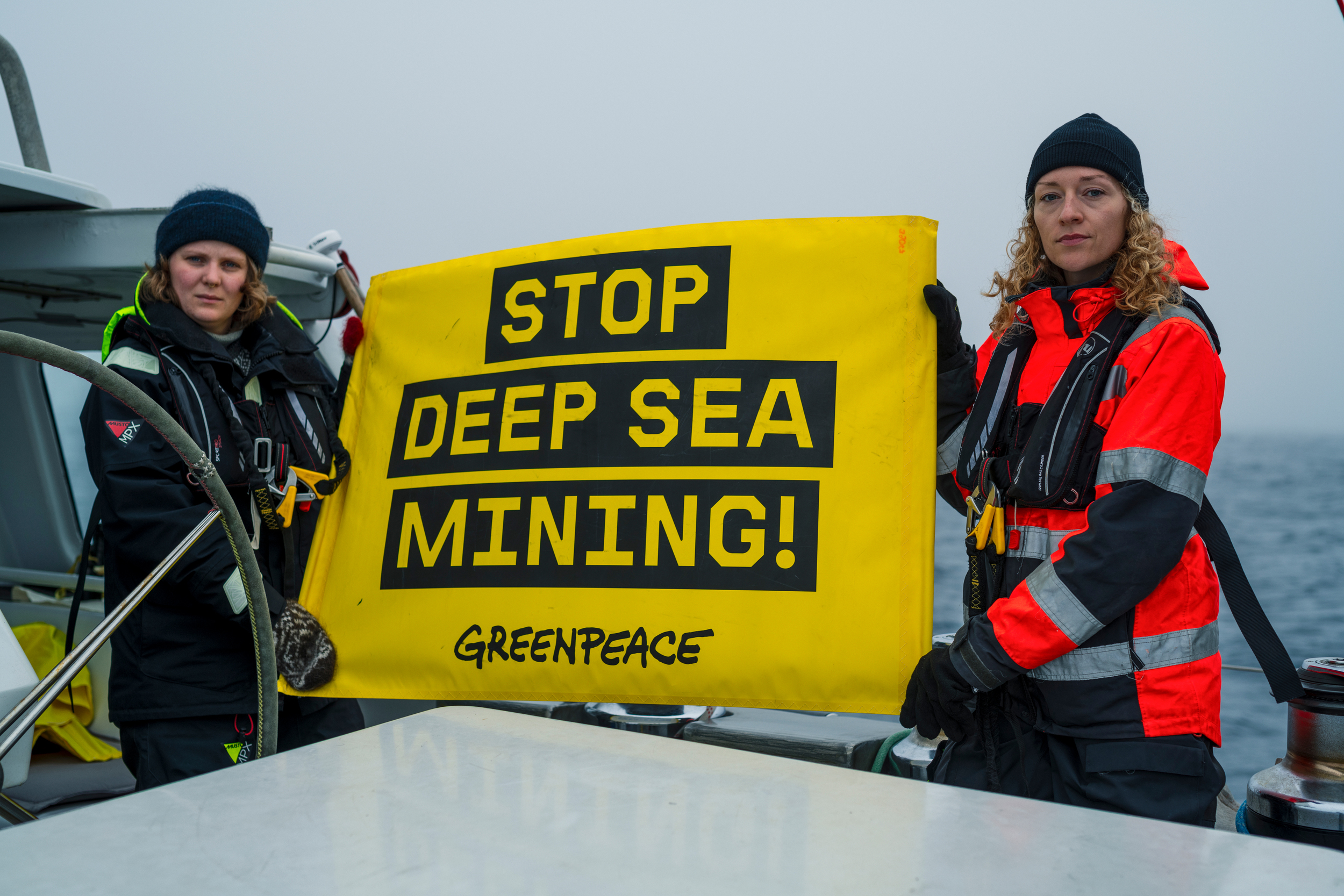 Greenpeace camaigners Haldis Tjeldflaat Helle and Franziska Saalmann hold a banner with the words "Stop Deep Sea Mining!" onboard the Witness. Credit: Christian Åslund/Greenpeace