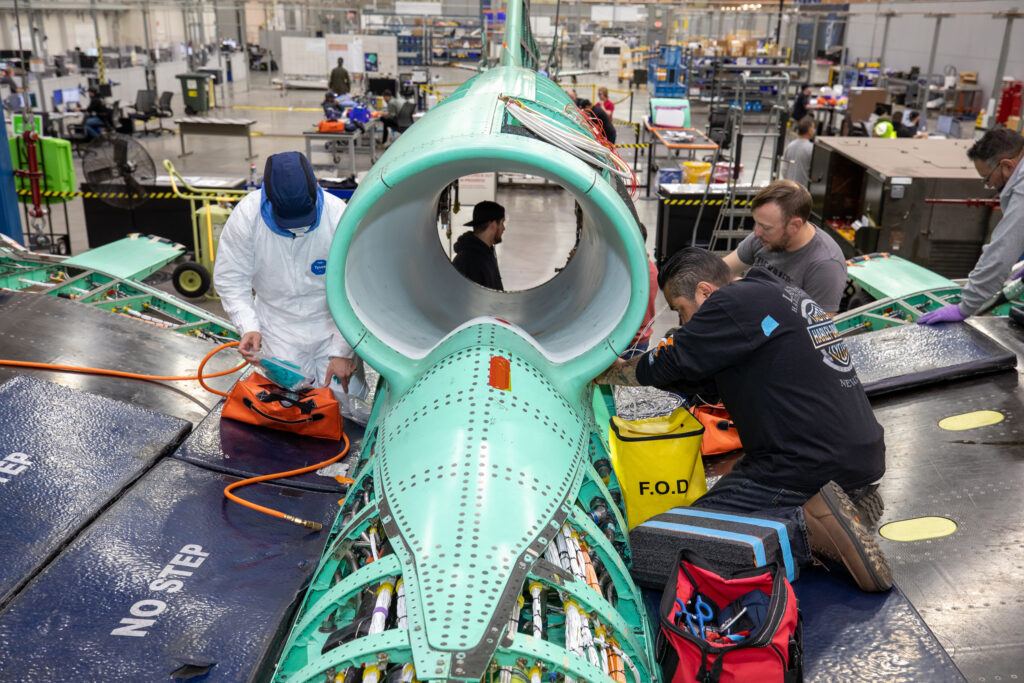 The X-59 team working on the aircraft’s wiring around the engine inlet prior to the engine being installed. Credit: Garry Tice/Lockheed Martin