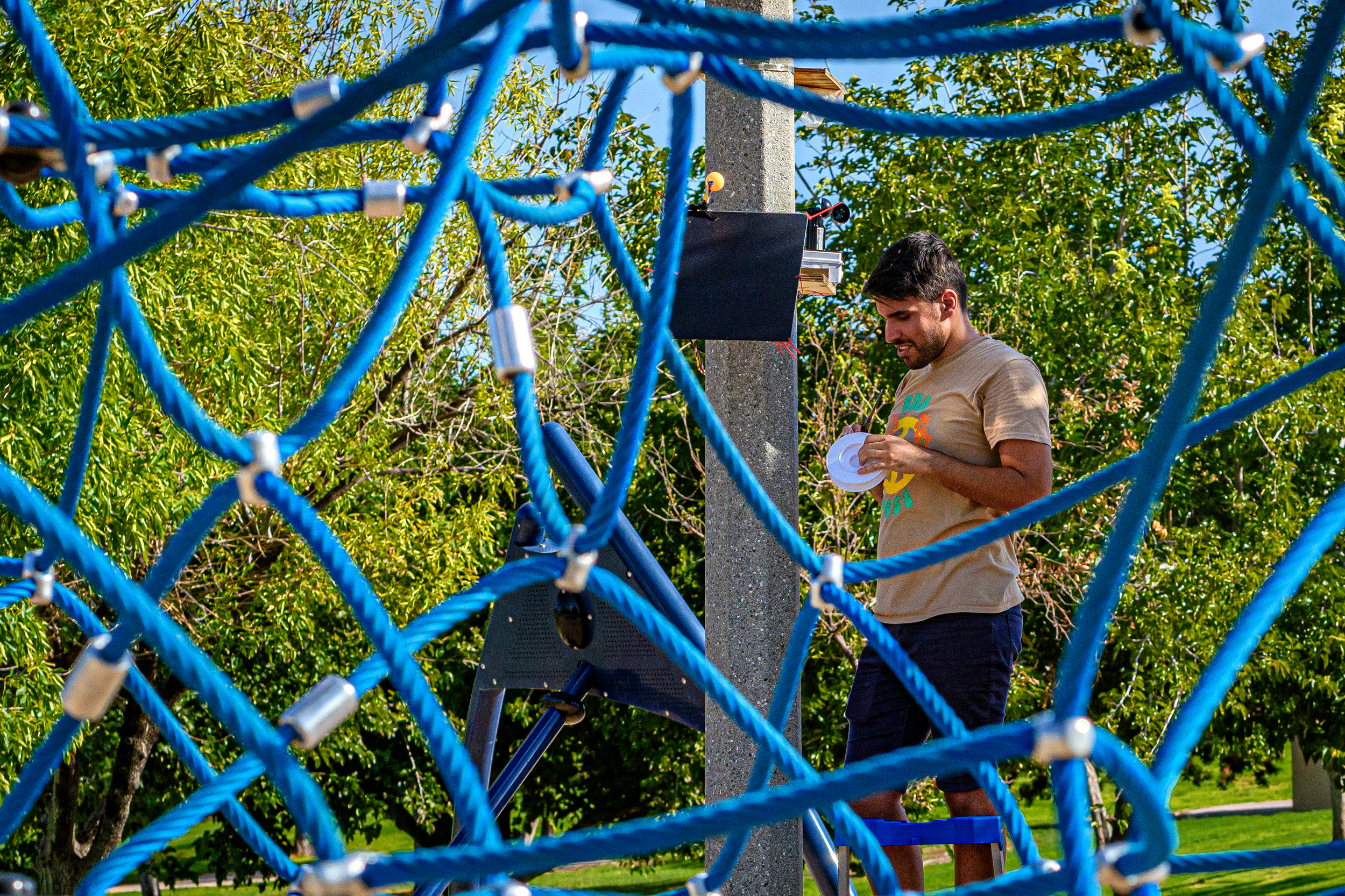 Pouya Shaeri, a graduate student conducting research with Arizona State University’s SHaDe Lab, adjusts one of the MaRTiny devices at Kiwanis Park. Credit: Kevin Hurley/Inside Climate News