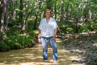 Andrea Childers stands in the creek on her property, which sits next to the Moriah Energy Center site in southeastern Person County.