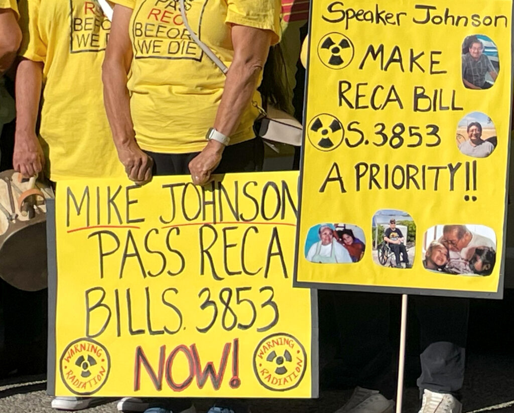 Supporters of RECA carry signs with photos of family members sickened by exposure to radioactive materials. Credit: Noel Lyn Smith/Inside Climate News